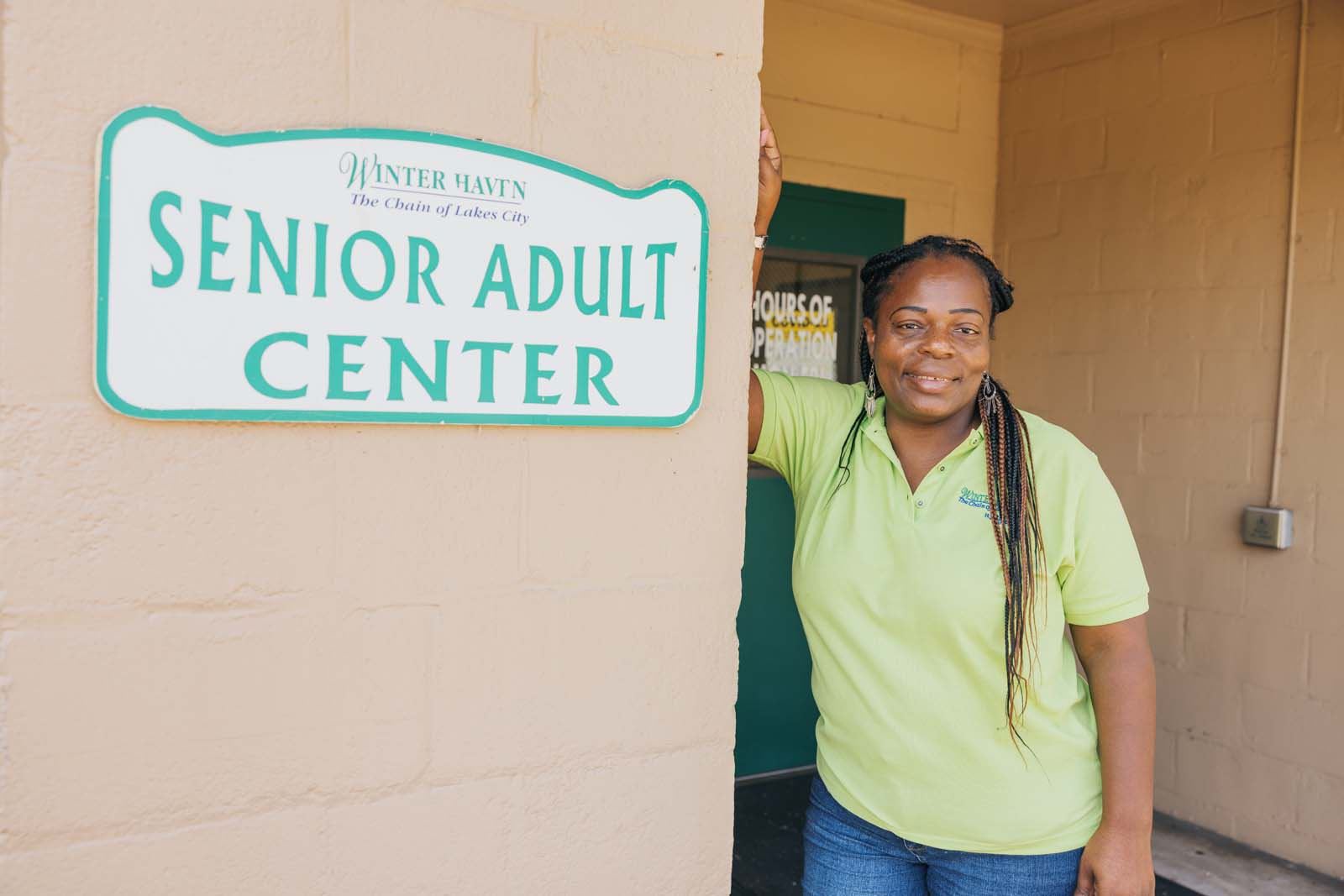 lady standing next to senior center sign. 