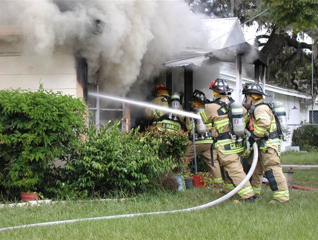 Firefighters Hosing a House Filled with Smoke